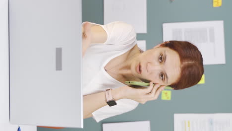 Vertical-video-of-Woman-using-laptop-nervously-talking-on-the-phone.
